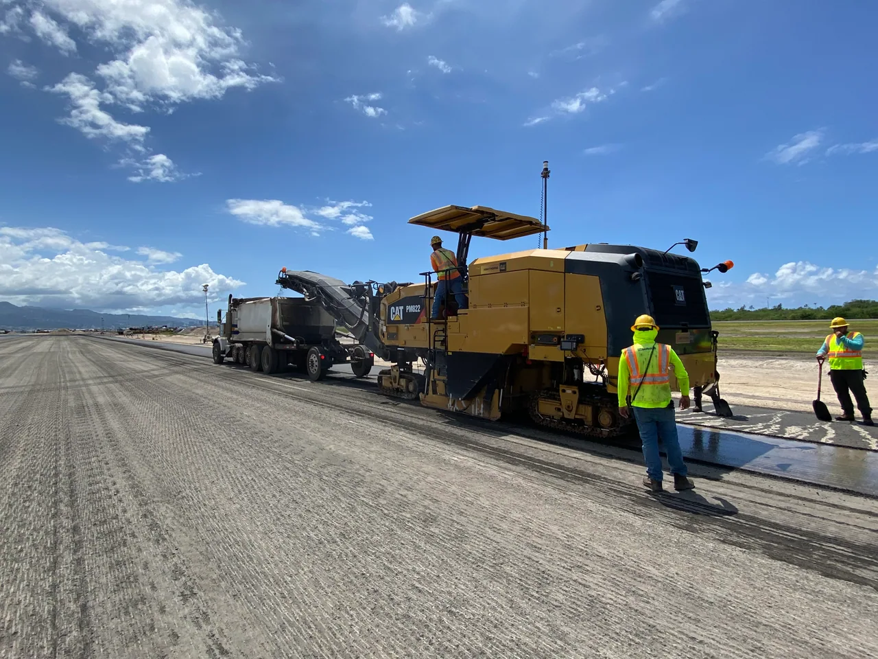 A milling machine and crew working along the airport runway.