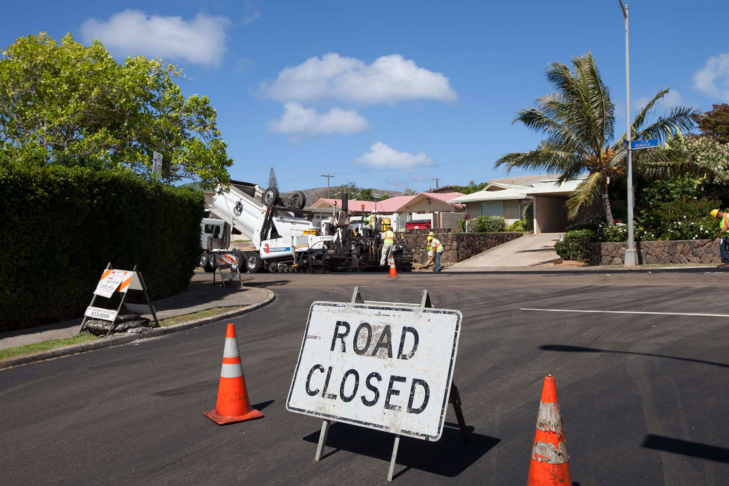 Freshly paved residential road with road closure signs and paving equipment