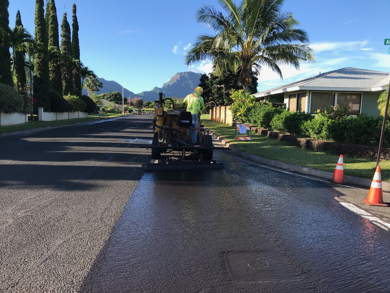 Worker applying pavement preservation treatment to a residential street in Hawaii