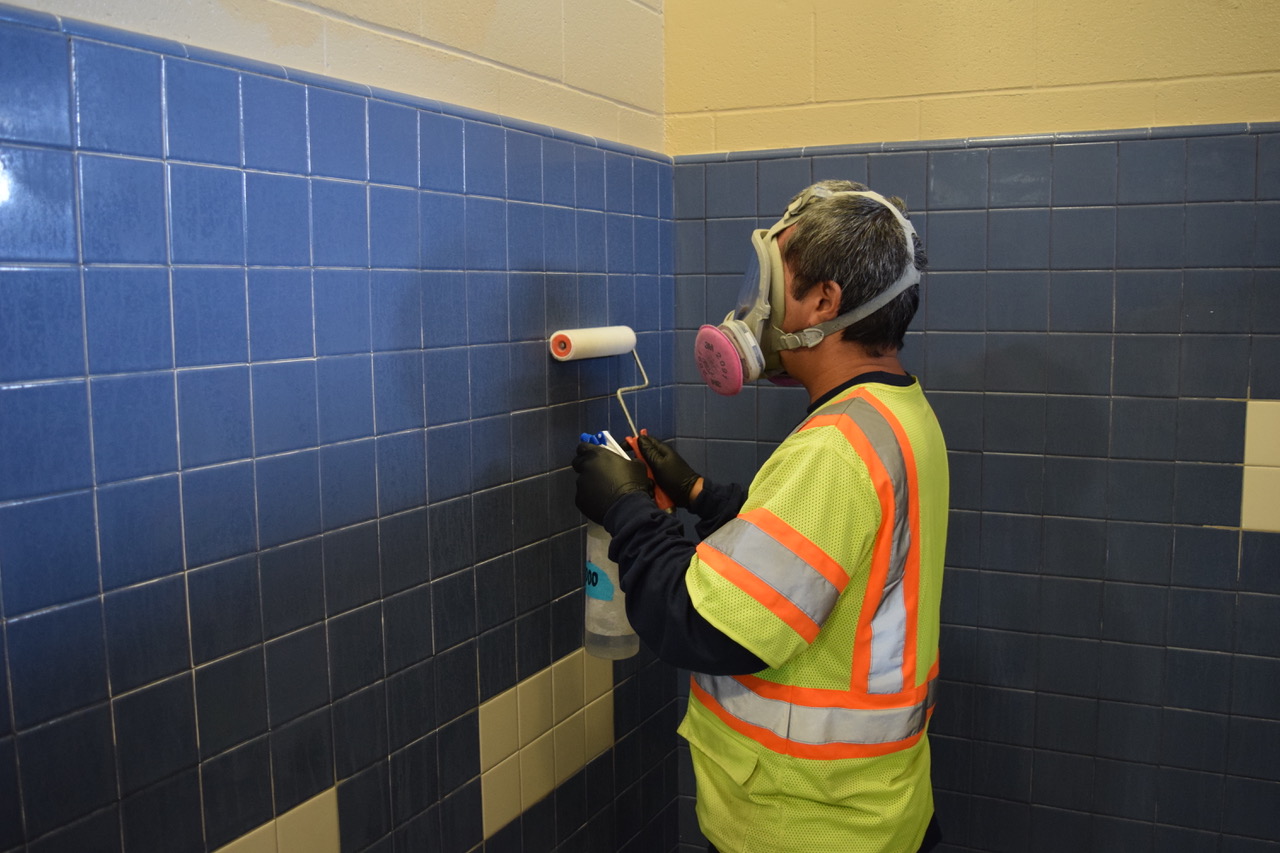 Worker applying protective coating to restroom tile at Kailua Beach