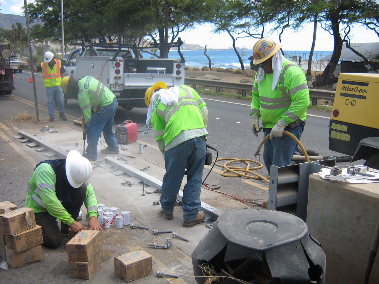 Roadway crew installing safety equipment beside a coastal highway