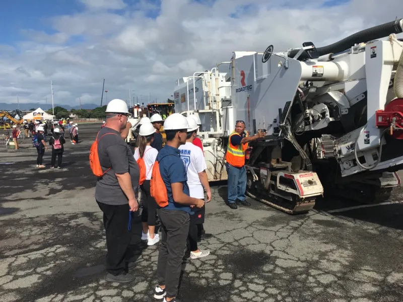 A Grace Pacific team member introduces students to road construction equipment at Hawaii Construction Career Day.